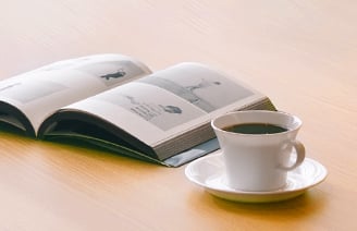 本とコーヒーが机の上に置かれたイメージ