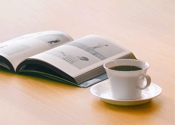 本とコーヒーが机の上に置かれたイメージ